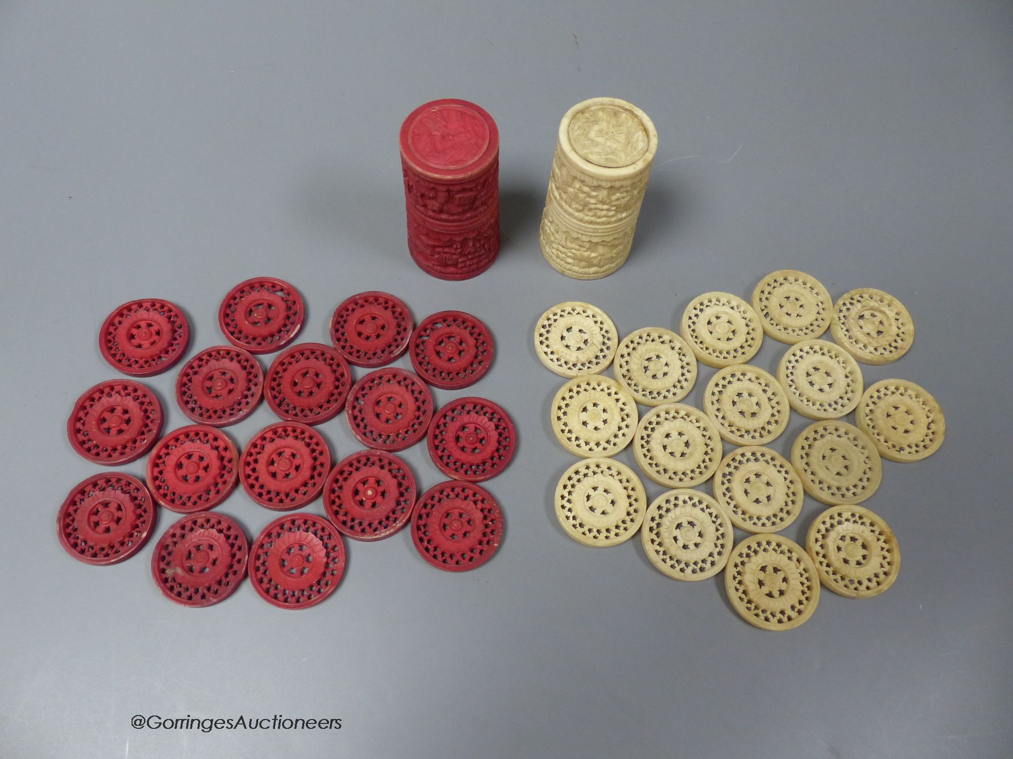 A Cantonese carved red stained and natural ivory draught set, including two shakers (18)